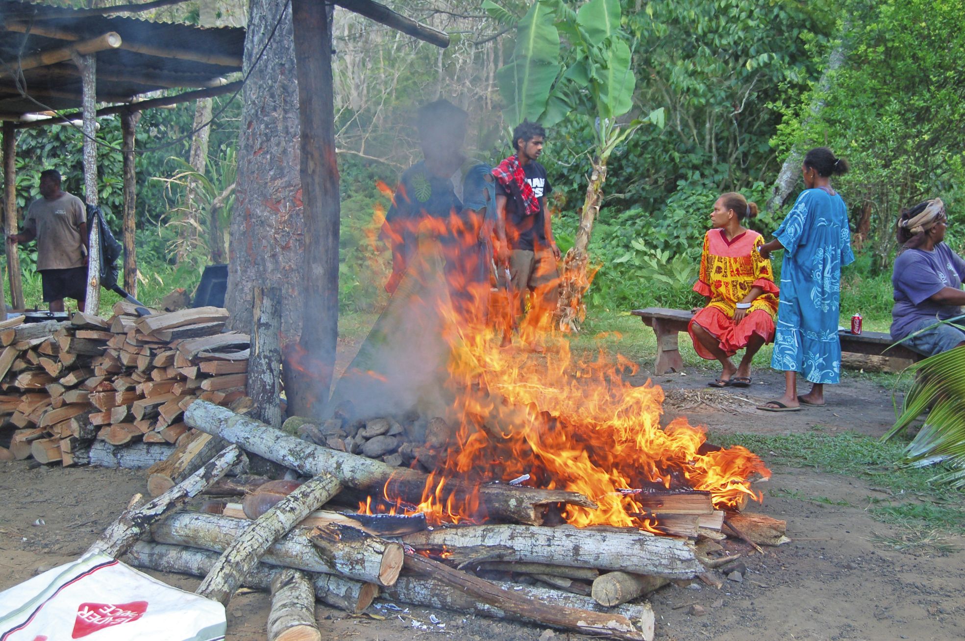 Les flammes chauffent les pierres du four traditionnel, où cuiront ensuite les bougnas et autres préparations.