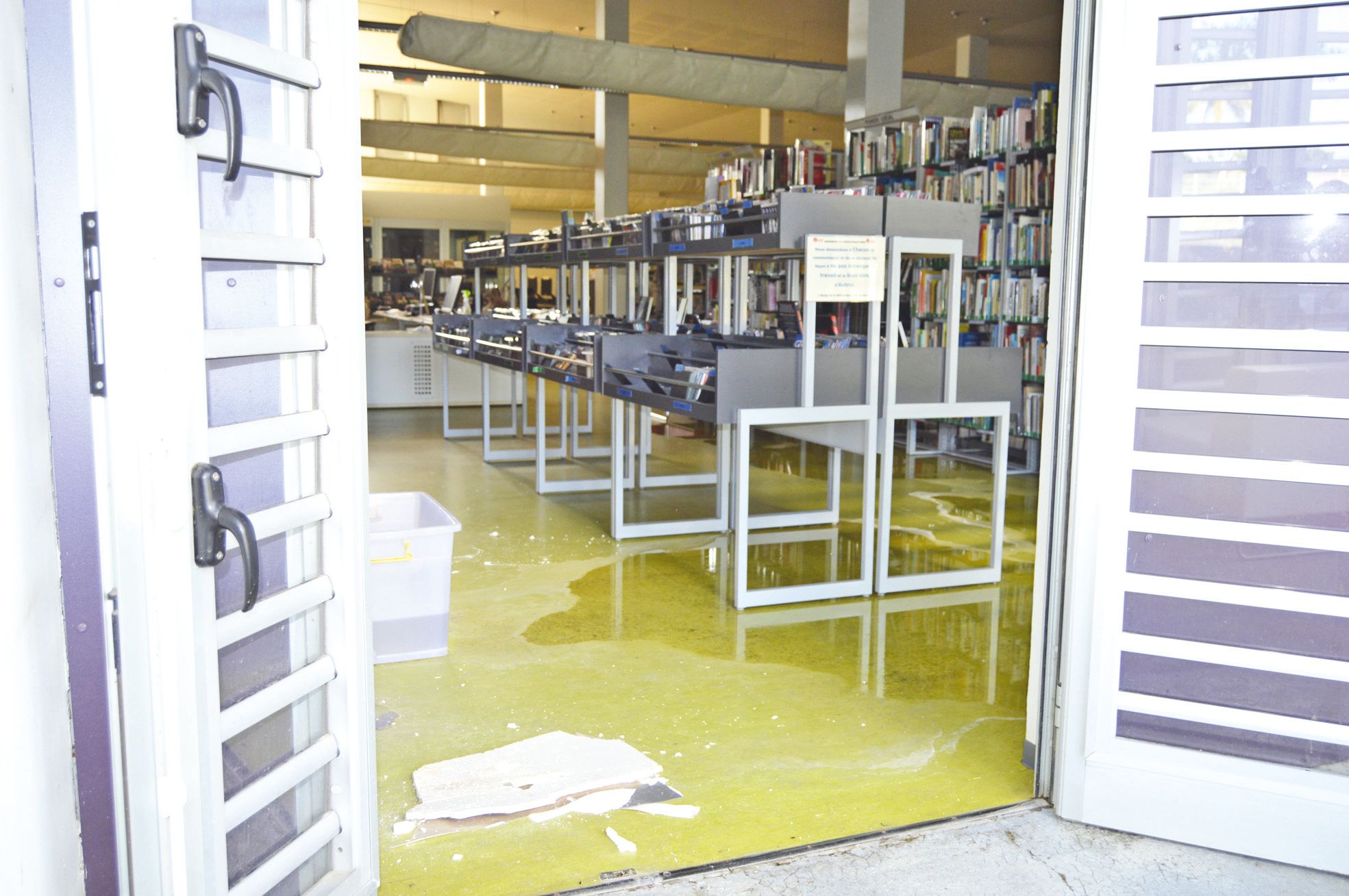La salle de prêt et de consultation, vue depuis la terrasse extérieure.  Du plâtre qui couvrait un tunnel de câbles est au sol
