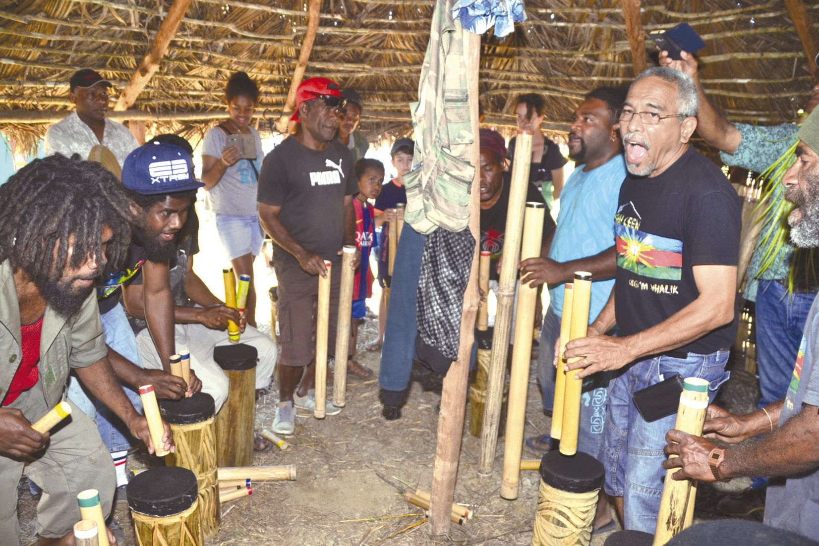 A l’ombre de la case construite en 2016, Hervé Lecren a rassemblé autour de lui musiciens et visiteurs. Ici, ils testent les tubes de bambou. « C’est l’instrument traditionnel détourné », explique Hervé Lecren. « Ça devient un instrument collectif où chac