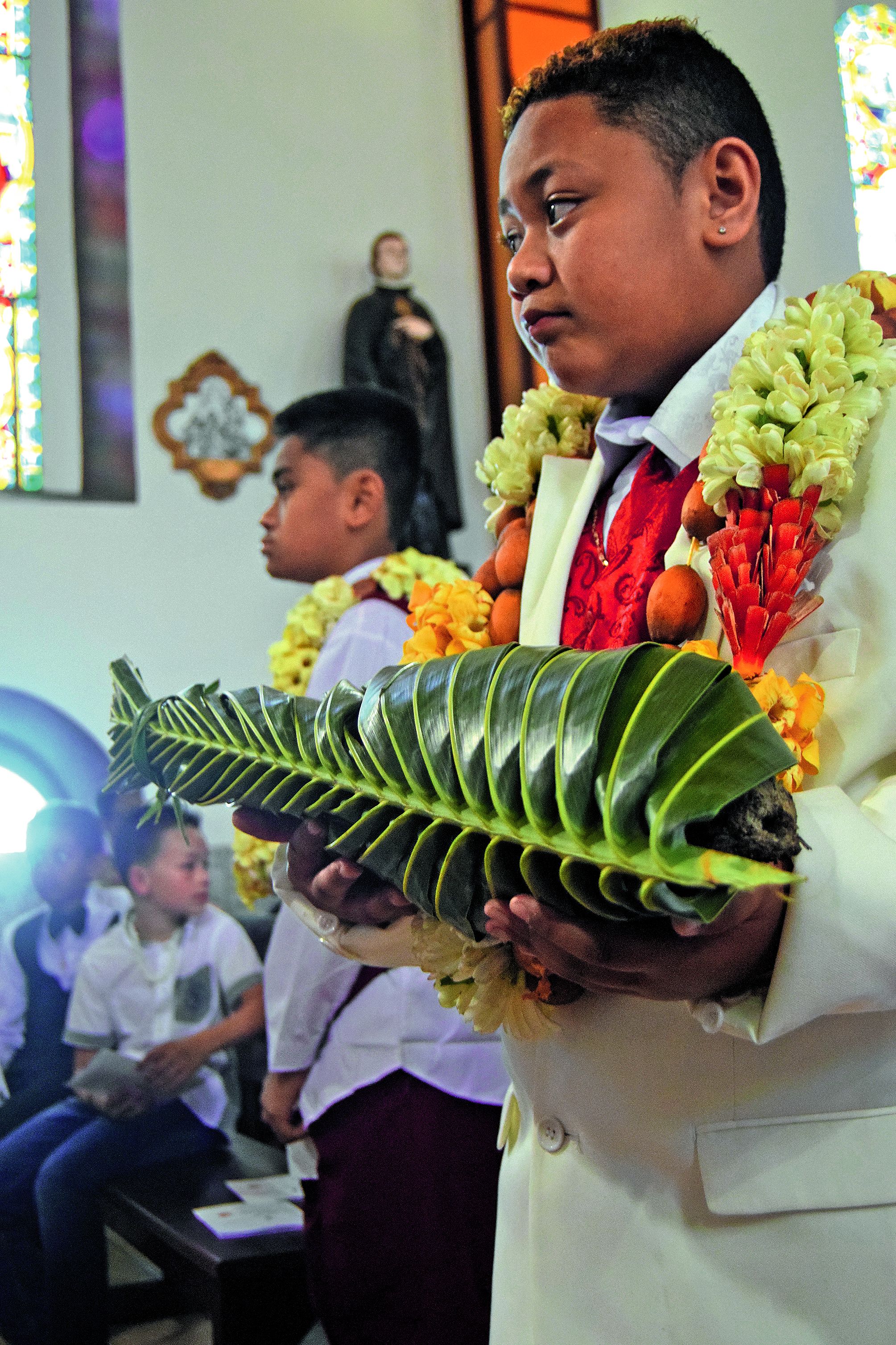 Parmi les rituels de la Communion, il y a le dépôt d’offrandes devant l’autel, fruits, vin, ou cette igname soigneusement emballée.