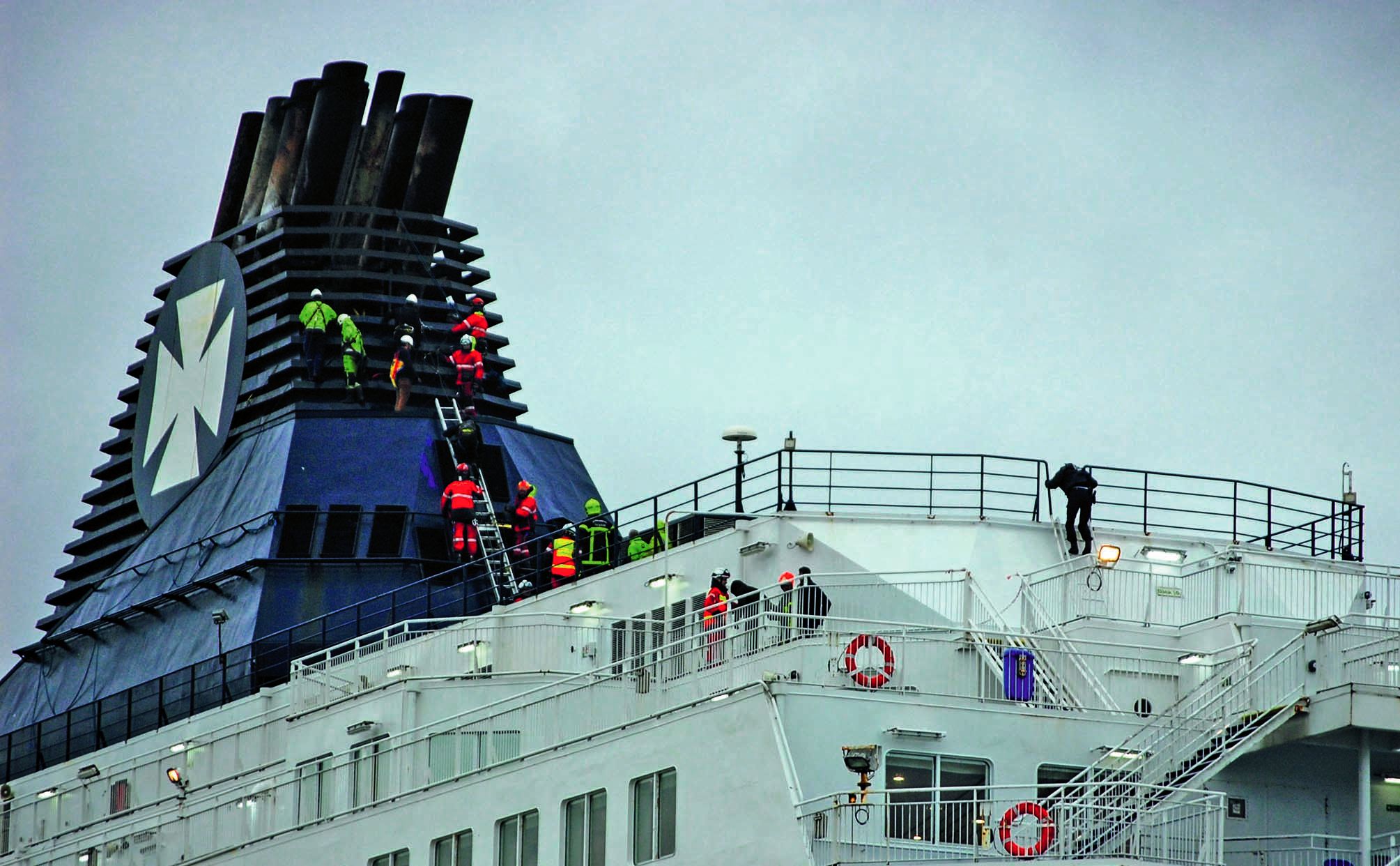 Les sapeurs-pompiers du Grimp (Groupe de reconnaissance et d’intervention en milieu périlleux) tentant de faire descendre les migrants du haut de la cheminée du ferry Calais seaways, qui venait d’arriver de Douvres, en Angleterre.Photo Bernard Barron/AFP