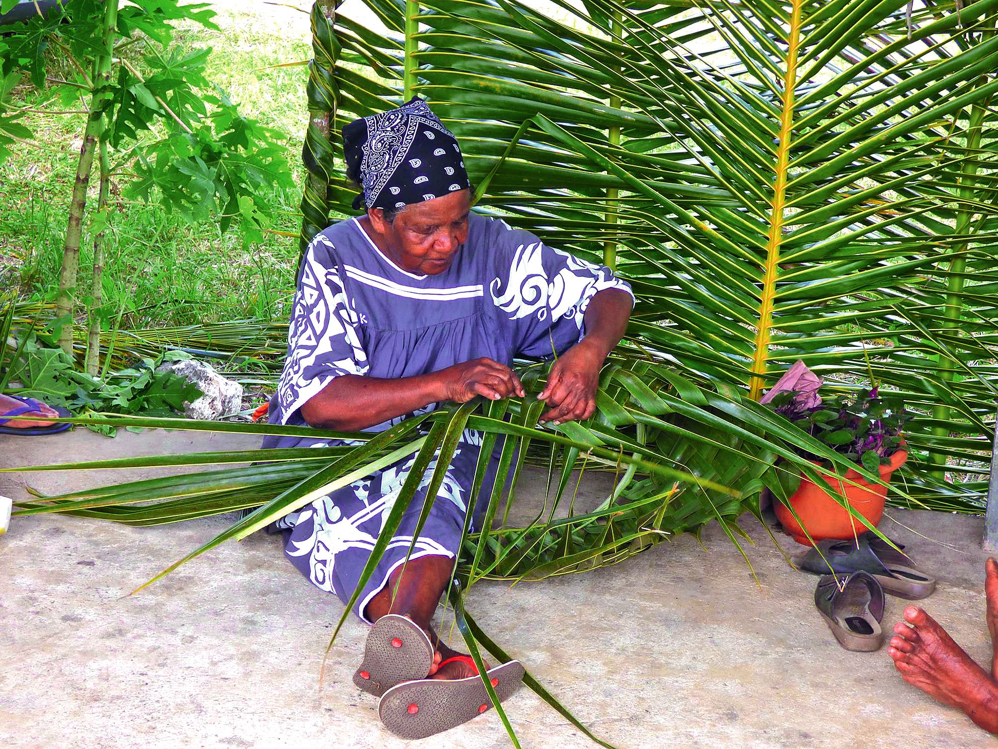 Mamy Josiane a réalisé des sacs tressés en feuilles de cocotier pour le transport des produits achetés à la foire.