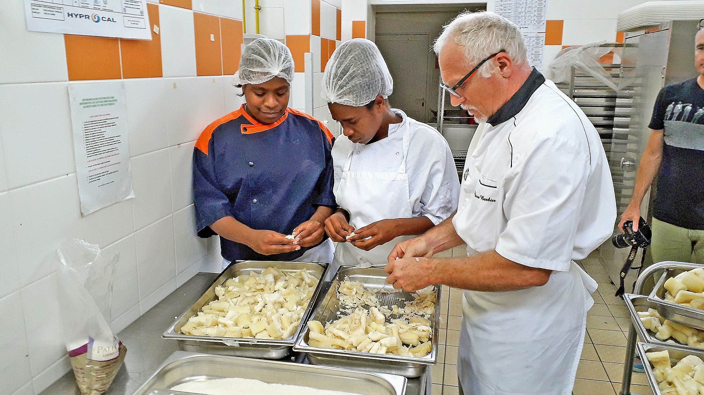 Préparation des maniocs par Efragie, à gauche, Eugénieau centre, deux élèves internes en CAP Cuisine à l’ALPet Etienne Barbier, leur professeur.