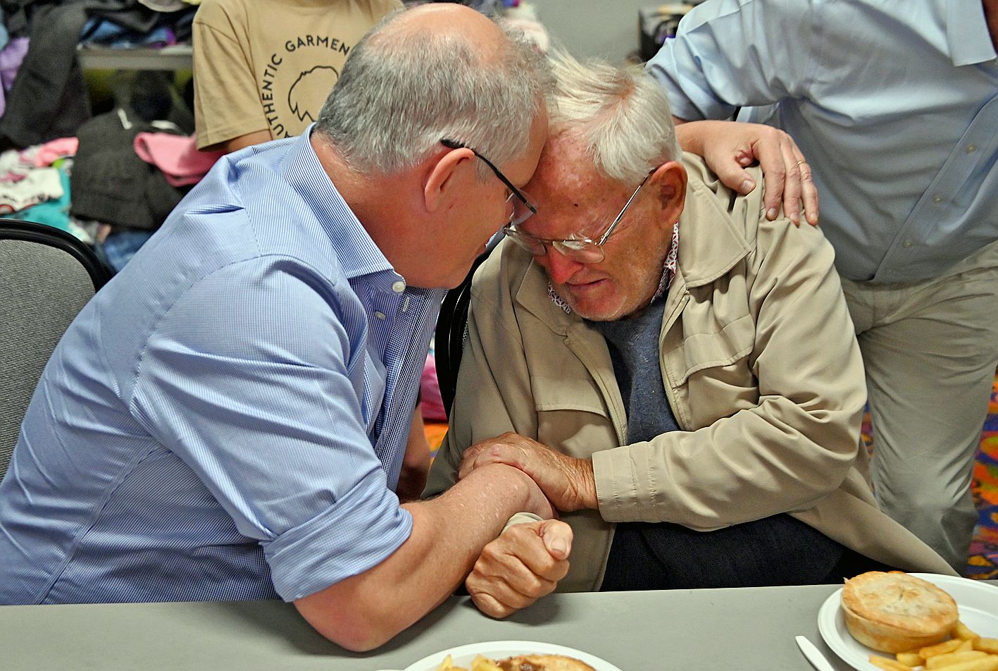 Le Premier ministre réconforte Owen Whalan, 85 ans, dans un centre d’évacuation à Taree. Le vieil homme a tout perdu.  AFP