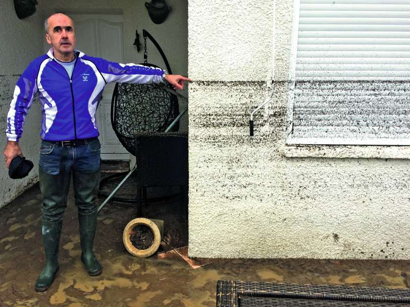 Un résident montre devant sa maison le niveau atteint par l\'eau dimanche à Villegailhenc. Photo AFP